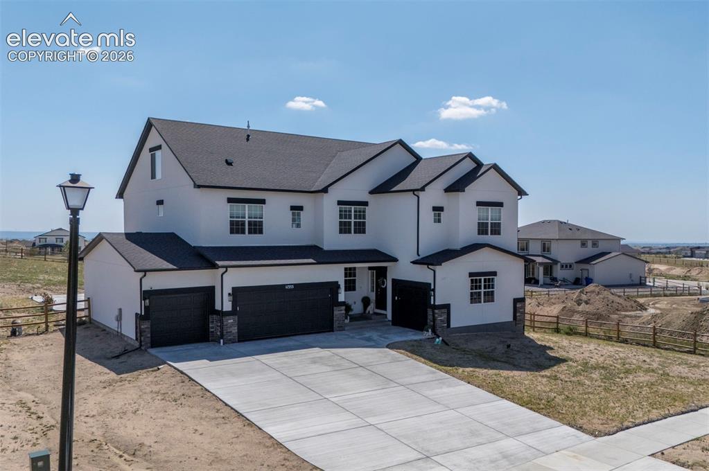 Image 1 of 45: Modern three-story residence featuring a light-toned exterior, dark roof, a