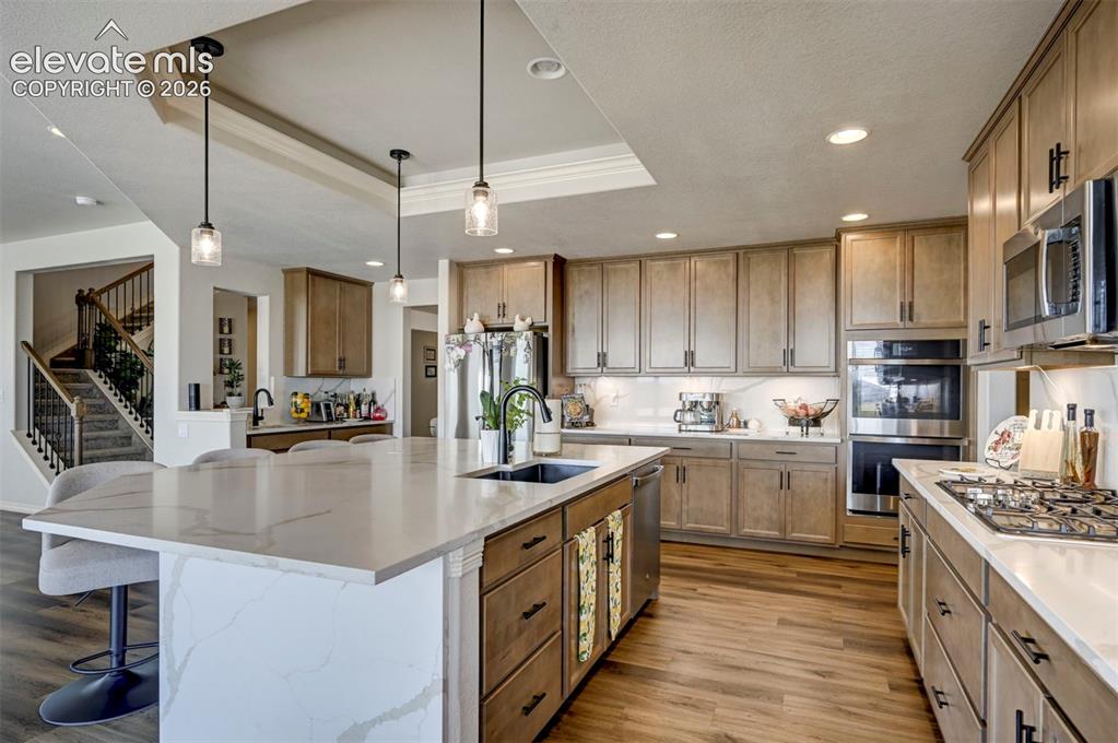 Image 17 of 45: Gourmet kitchen featuring a large island with a waterfall countertop, wood-