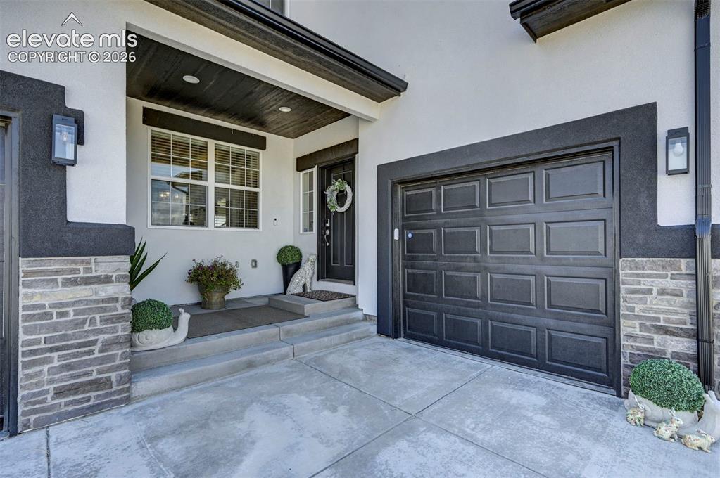 Image 2 of 45: Contemporary exterior with a paneled garage door and a covered entryway