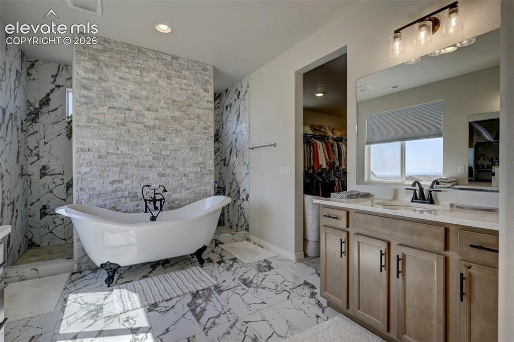 Image 22 of 45: Bathroom featuring a freestanding clawfoot tub, floor-to-ceiling marbled ti