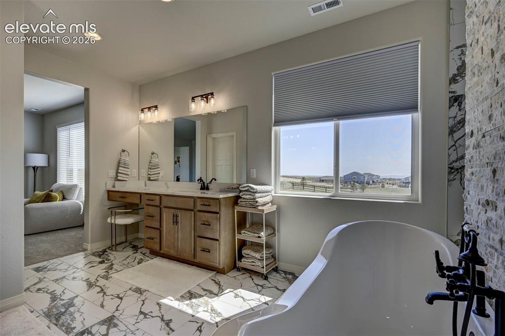 Image 24 of 45: Bathroom featuring a freestanding tub with matte black fixtures, a dual-sin