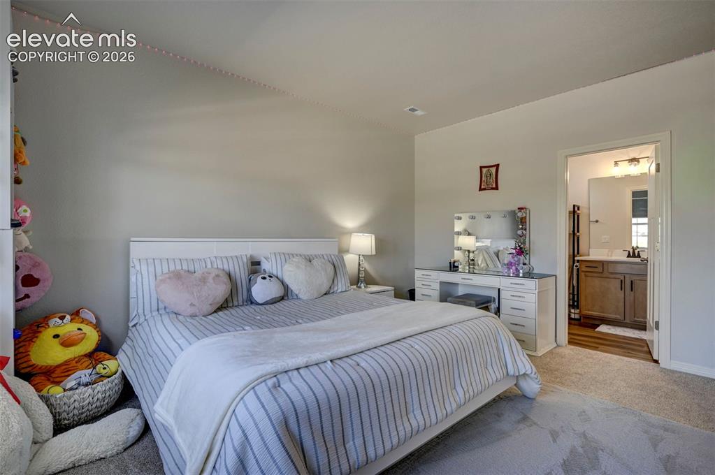 Image 26 of 45: Carpeted bedroom with neutral wall tones and a white headboard