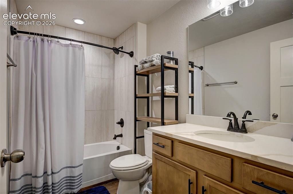 Image 36 of 45: Bathroom featuring a tub/shower combination with tile surround, a wood-fini