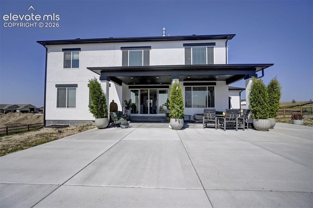 Image 44 of 45: White stucco exterior with black trim, featuring a covered patio, extensive