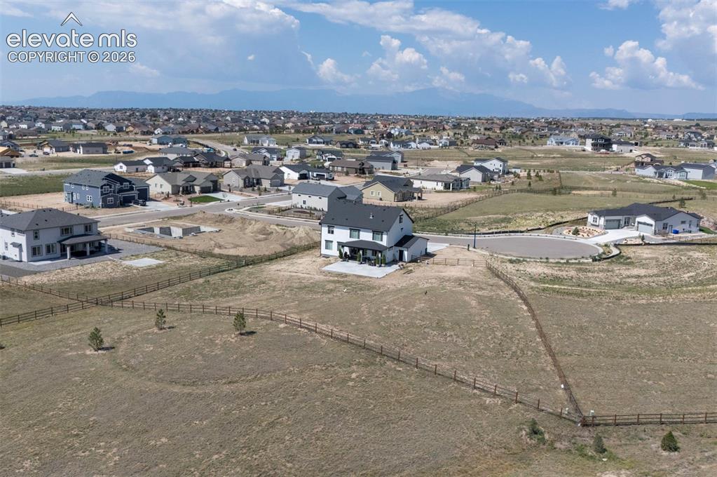Image 45 of 45: Spacious lot featuring perimeter fencing, several young trees, and a mounta