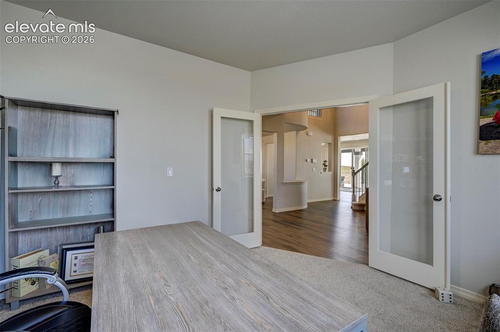 Image 9 of 45: Double French doorsnpanels open to a spacious entry hall featuring wood-fin