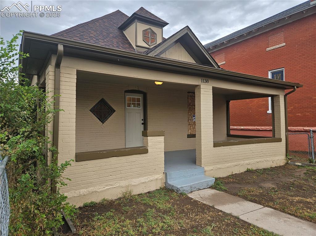 Caption: View of front of property featuring covered porch and brick siding