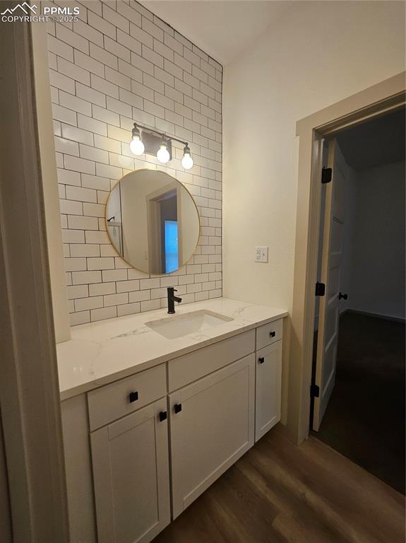 Image 10 of 23: Bathroom featuring wood finished floors, vanity, and tasteful backsplash