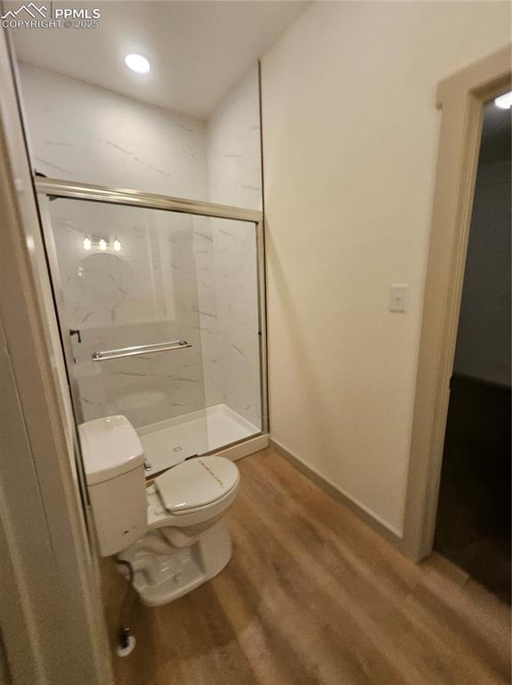 Image 11 of 23: Bathroom with a marble finish shower and wood finished floors
