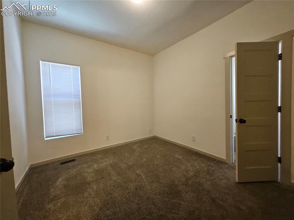 Image 13 of 23: Unfurnished room with dark colored carpet and vaulted ceiling