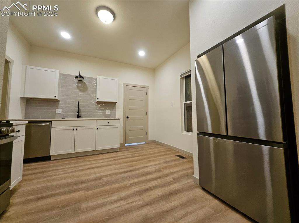 Image 17 of 23: Kitchen with appliances with stainless steel finishes, white cabinetry, tas