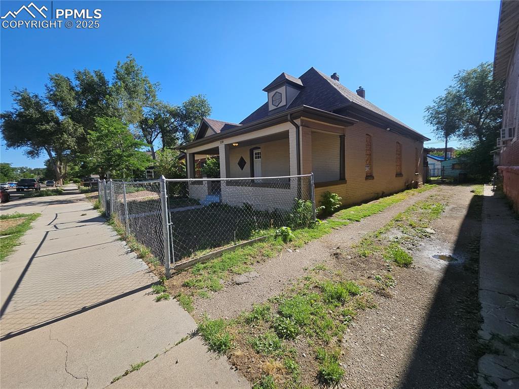 Image 2 of 23: View of side of home with brick siding, covered porch, and a chimney
