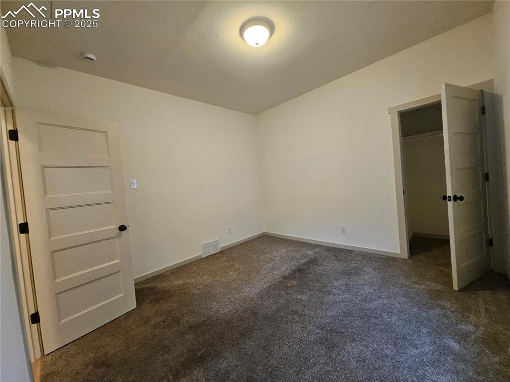 Image 8 of 23: Unfurnished bedroom with dark carpet, a spacious closet, and a closet
