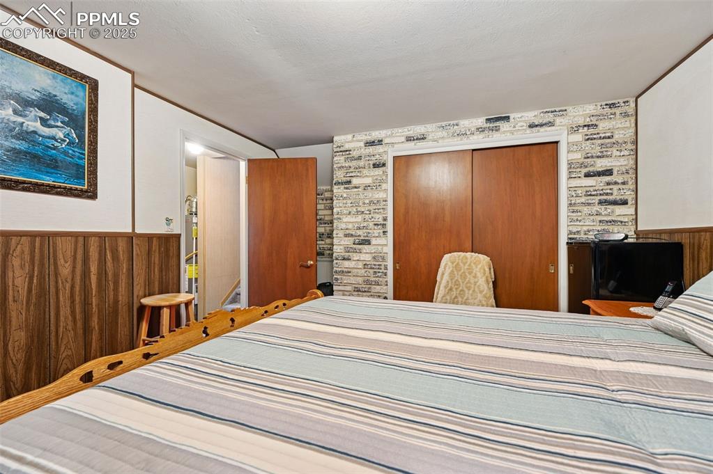 Image 15 of 23: Bedroom featuring a wainscoted wall, wood walls, and a closet