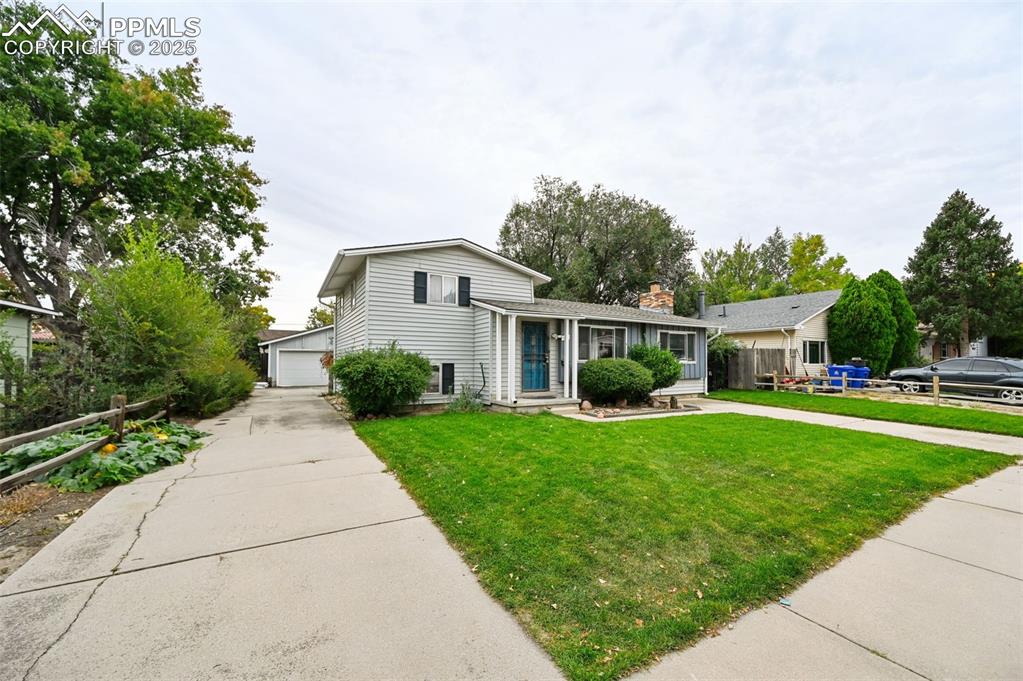 Image 2 of 23: Split level home with a chimney and a detached garage