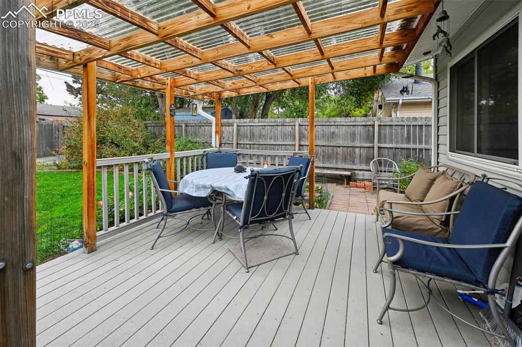 Image 21 of 23: Deck with outdoor dining area and a fenced backyard