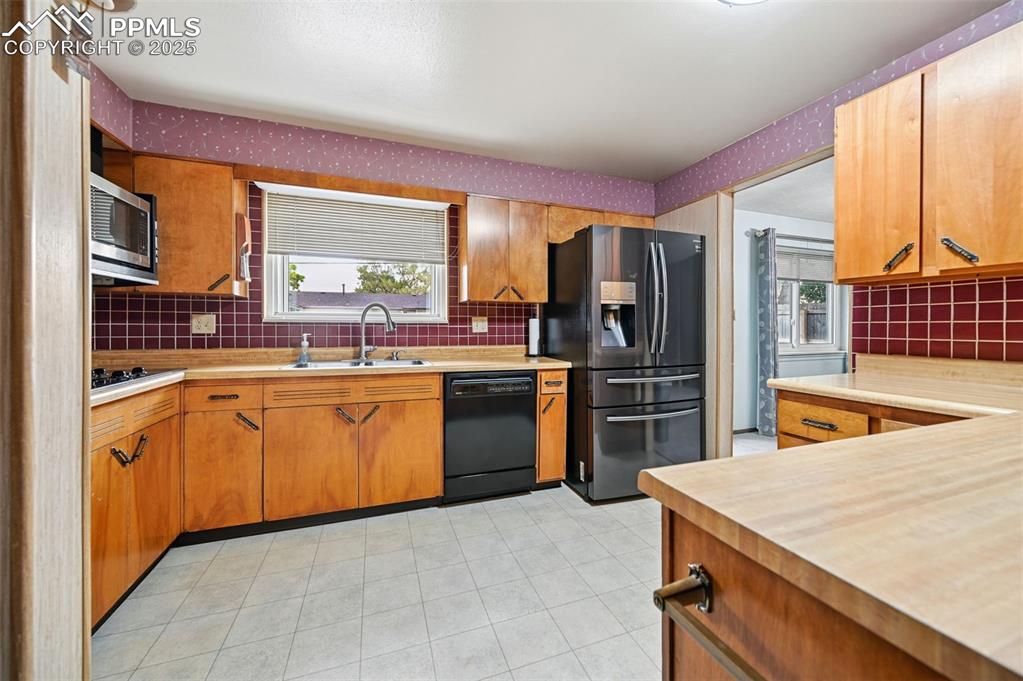 Image 6 of 23: Kitchen with decorative backsplash, refrigerator with ice dispenser, dishwa