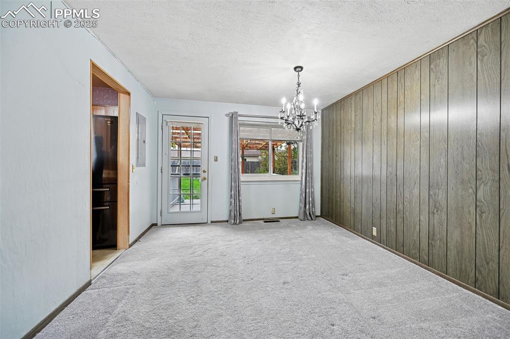 Image 9 of 23: Unfurnished dining area featuring a textured ceiling, a chandelier, carpet,