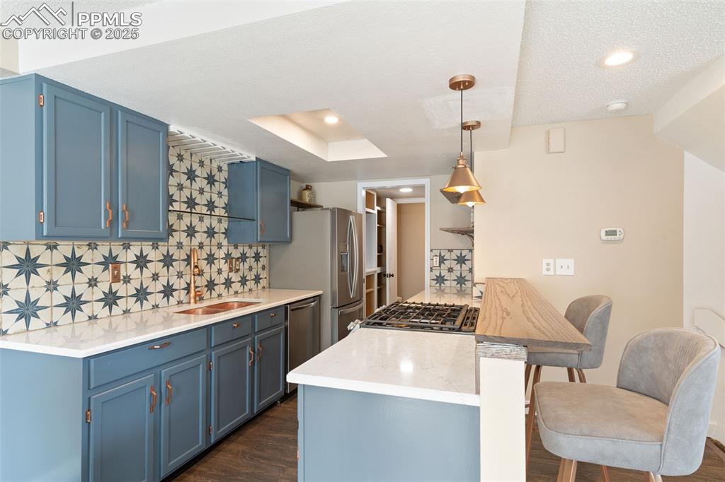 Image 14 of 34: Kitchen featuring blue cabinetry, backsplash, a peninsula, recessed lightin