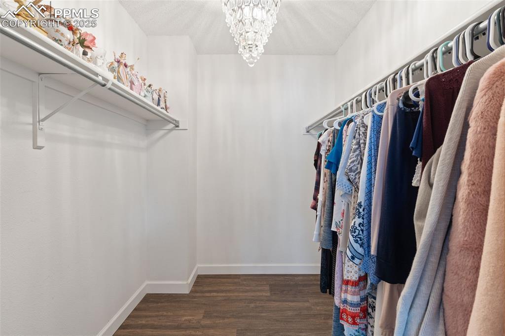 Image 21 of 34: Primary suite closet with plenty of storage and chandelier
