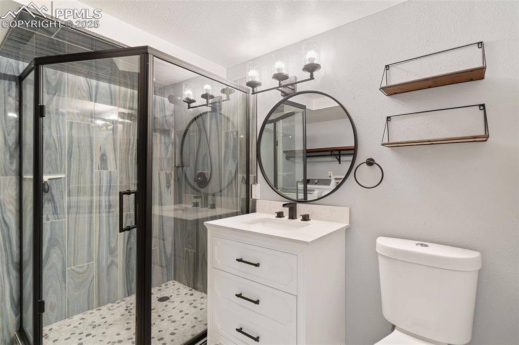 Image 28 of 34: Bathroom featuring vanity, a shower stall, a textured wall, and a textured