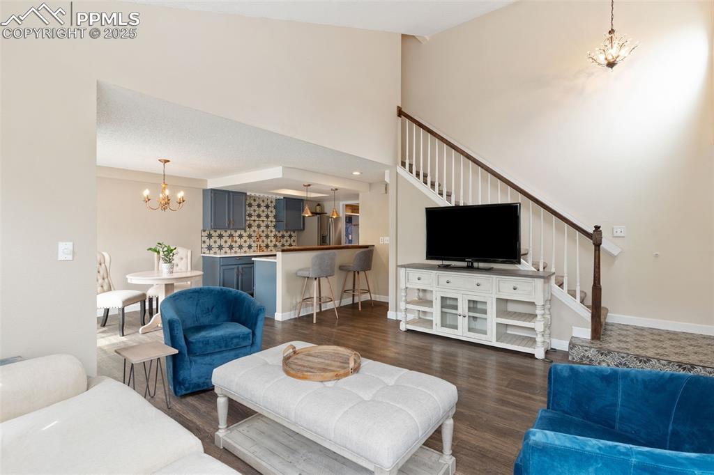 Image 4 of 34: Living room with a chandelier, stairway, dark wood-type flooring, and a tow