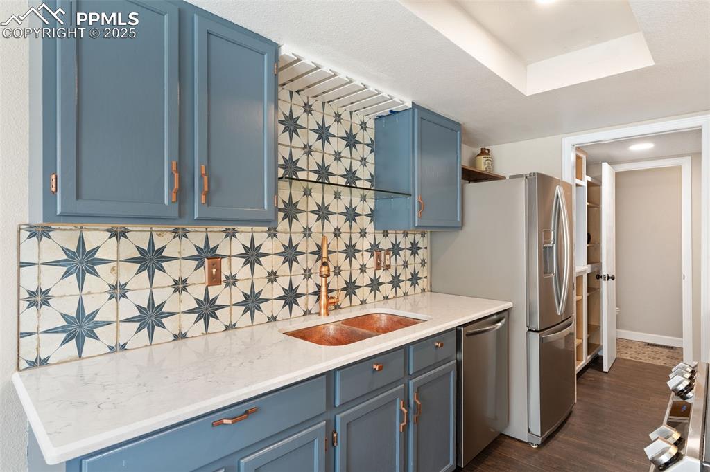 Image 5 of 34: Kitchen featuring blue cabinets, tasteful custom backsplash, range, dishwas