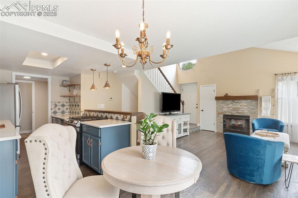 Image 6 of 34: Dining space featuring dark wood-type flooring, a stone fireplace, and a ch