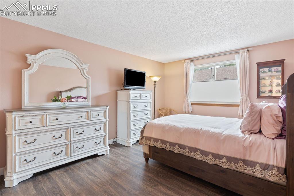 Image 7 of 34: Bedroom featuring a textured ceiling and dark wood finished floors