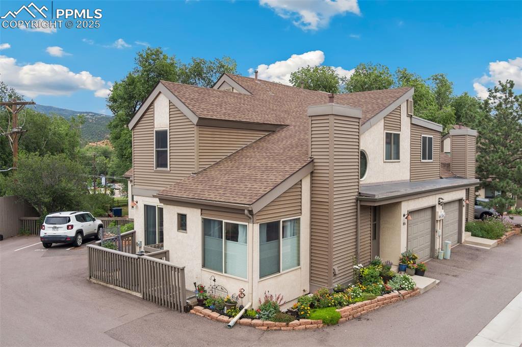 Image 8 of 34: Beautiful gardens enhance the front of the home with stucco, durable vinyl