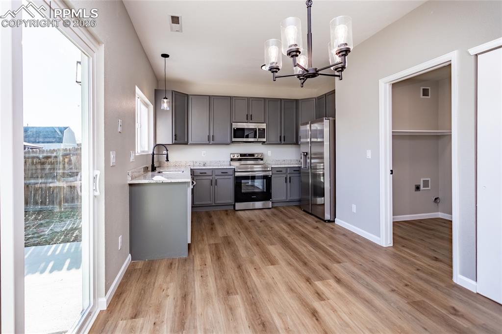 Image 15 of 42: Notice the beautiful light fixtures through, LVP flooring, and the laundry
