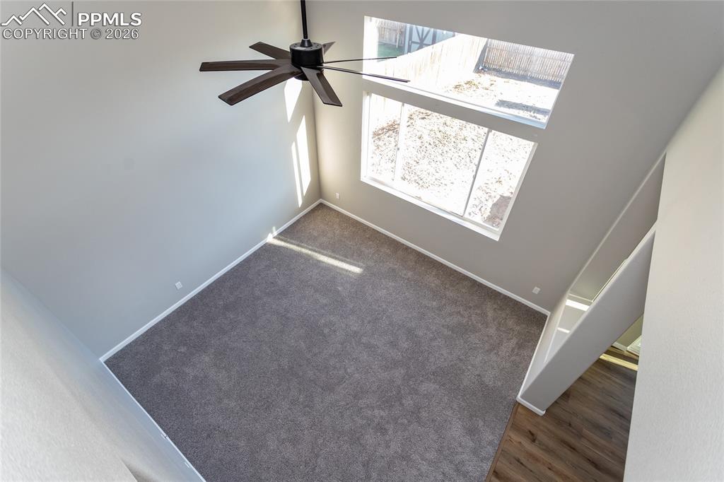 Image 21 of 42: The stairs overlook the 2 story living room with lovely ceiling fan.