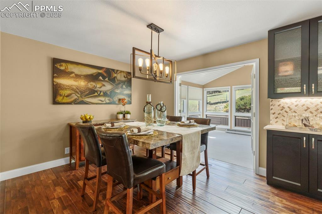 Image 10 of 46: Dining room with dark wood-style floors, baseboard heating, and a chandelie