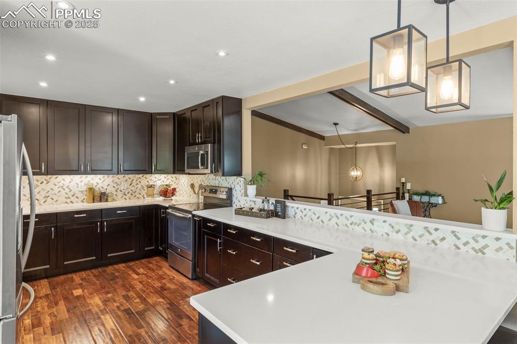 Image 13 of 46: Kitchen featuring decorative light fixtures, backsplash, appliances with st