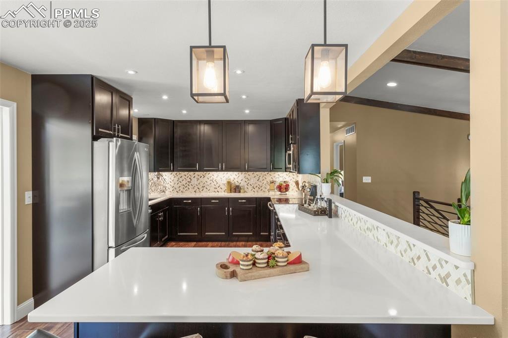 Image 14 of 46: Kitchen with backsplash, a peninsula, stainless steel appliances, a breakfa