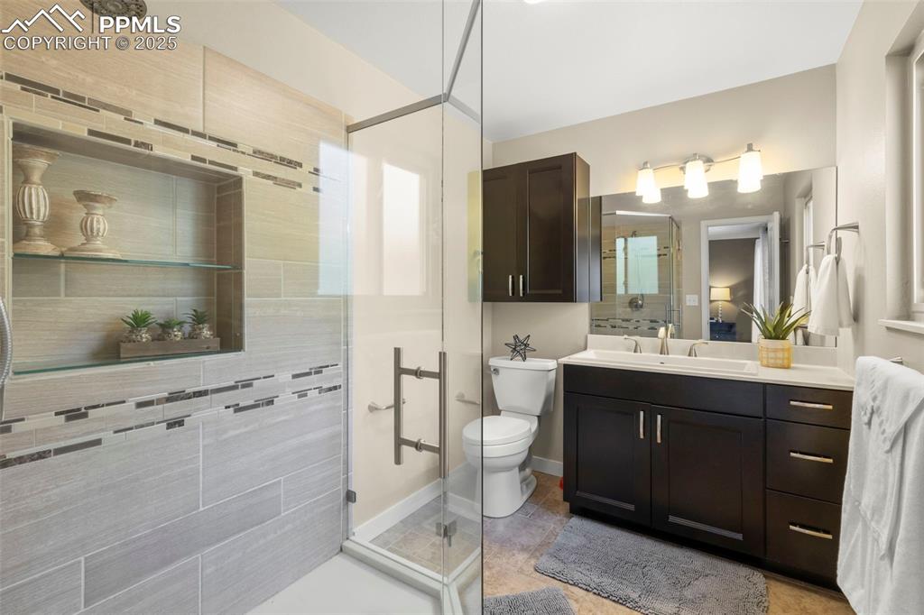 Image 27 of 46: Bathroom with a stall shower, vanity, and light tile patterned floors
