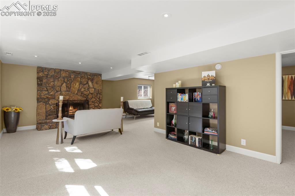 Image 29 of 46: Living room featuring a stone fireplace and carpet flooring