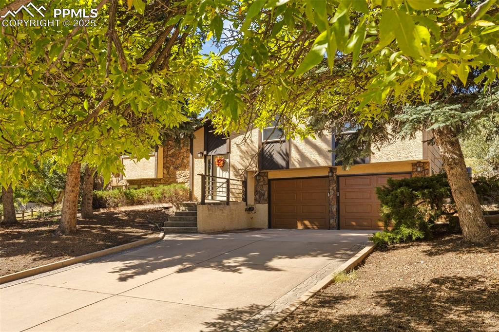 Image 3 of 46: View of front facade with stone siding and concrete driveway