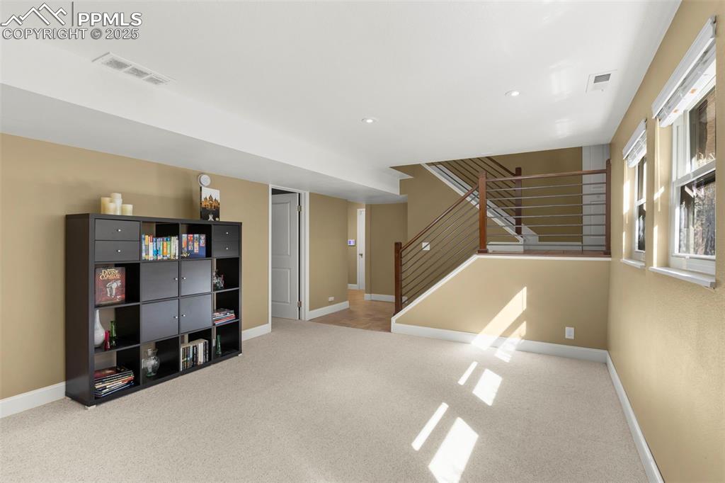 Image 32 of 46: Below grade area featuring light colored carpet, stairway, and recessed lig