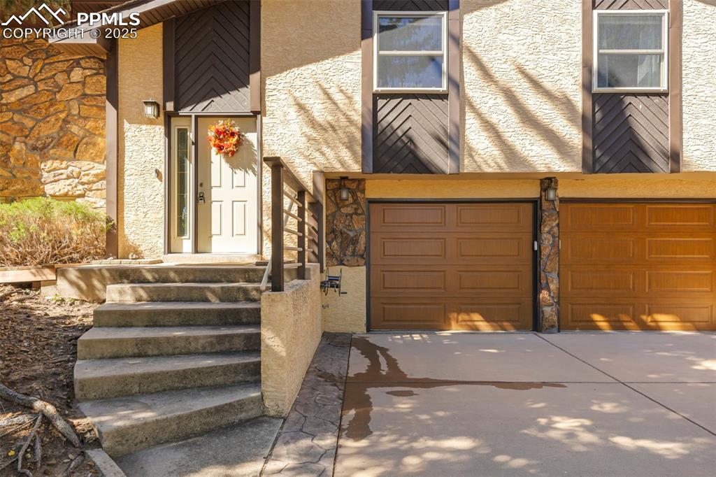 Image 4 of 46: Mid-century home with stone siding, an attached garage, concrete driveway, 