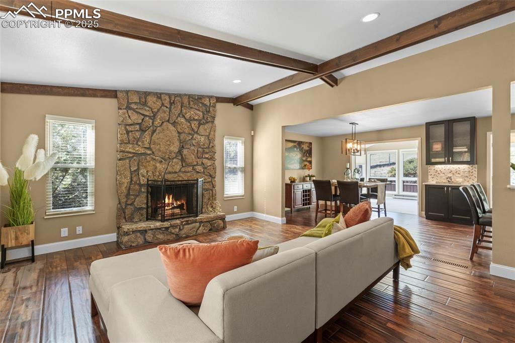 Image 8 of 46: Living area with a stone fireplace, a chandelier, dark wood-style flooring,