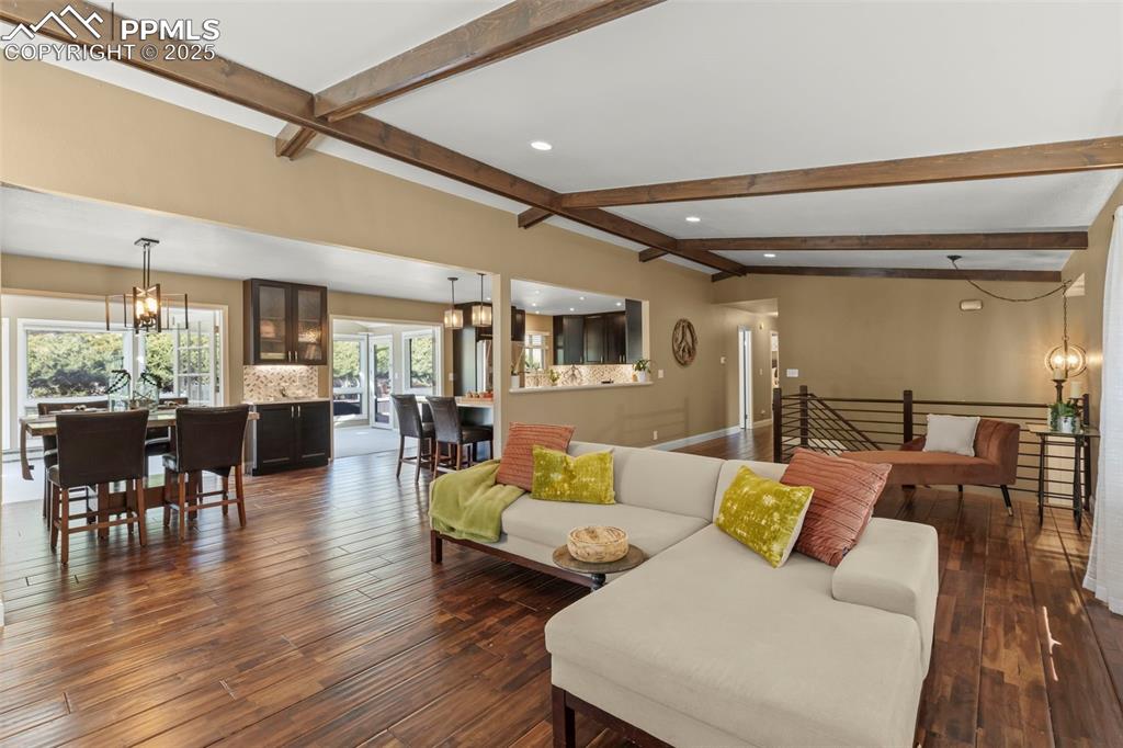 Image 9 of 46: Living room with a chandelier, dark wood-style flooring, beamed ceiling, an