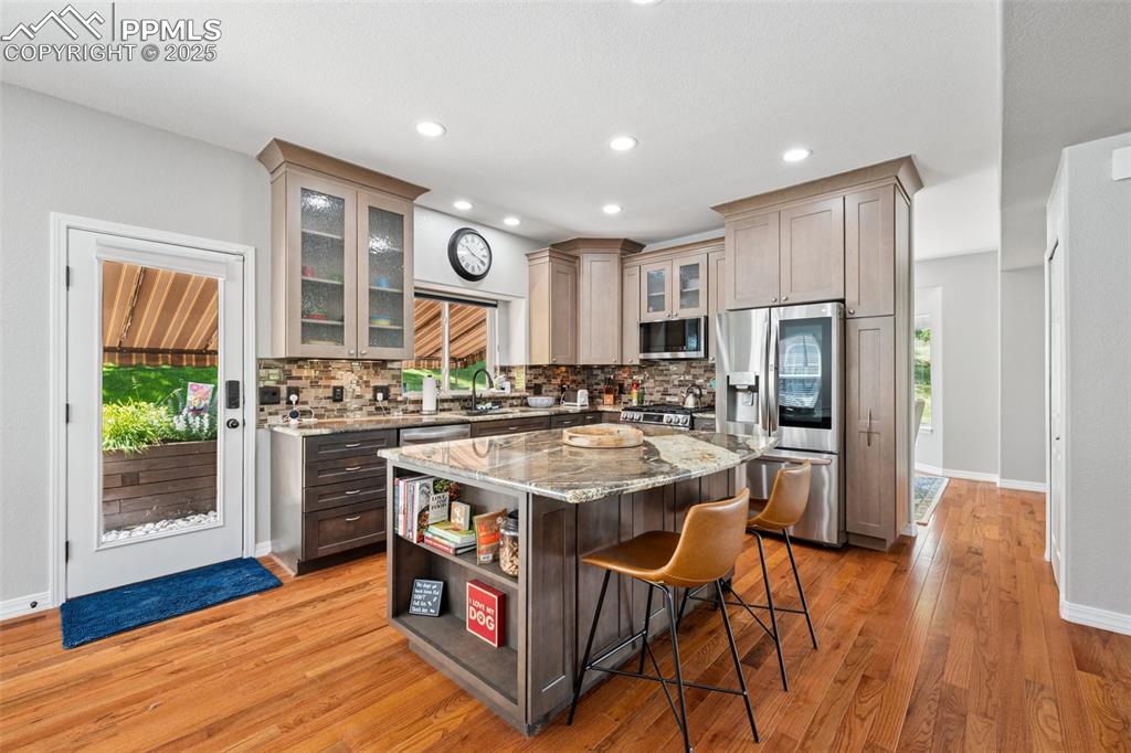 Image 11 of 50: Kitchen featuring appliances with stainless steel finishes, a breakfast bar