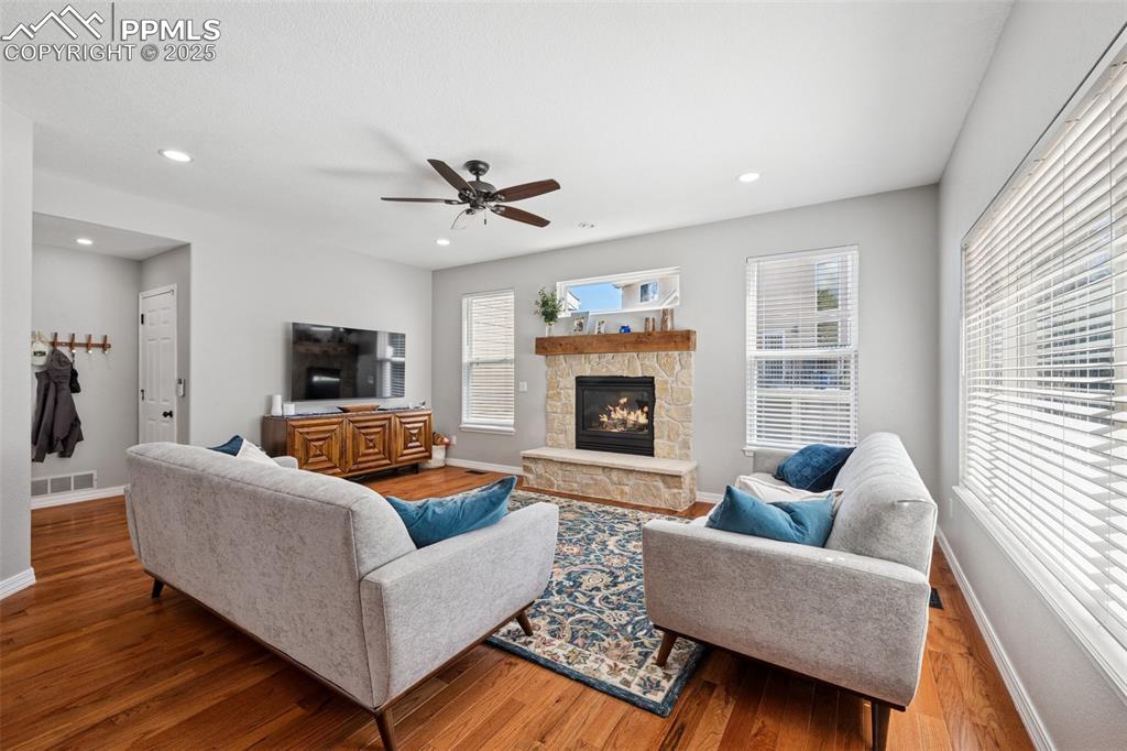 Image 12 of 50: Living area with wood finished floors, plenty of natural light, a fireplace