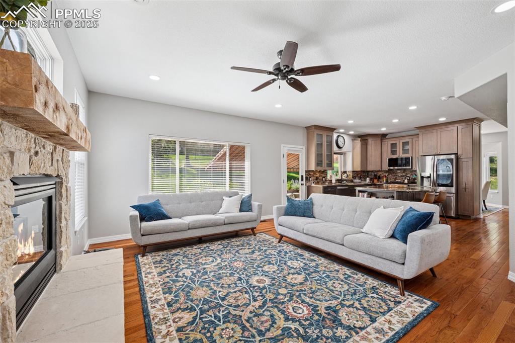 Image 15 of 50: Living room with a fireplace, ceiling fan, wood finished floors, and recess