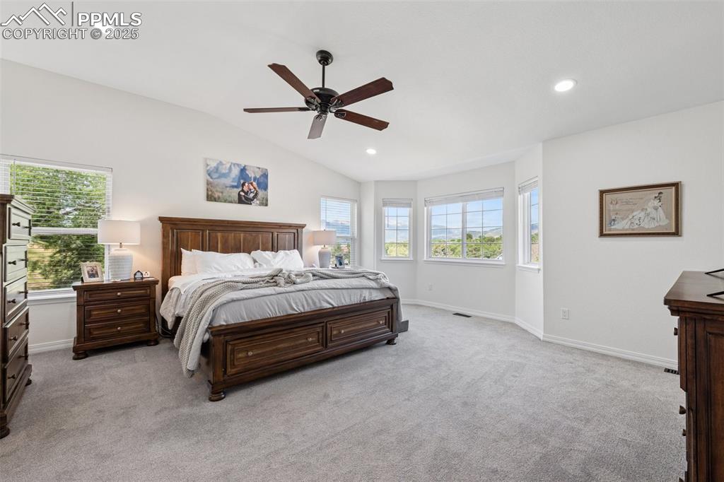 Image 25 of 50: Bedroom featuring light colored carpet, lofted ceiling, a ceiling fan, and