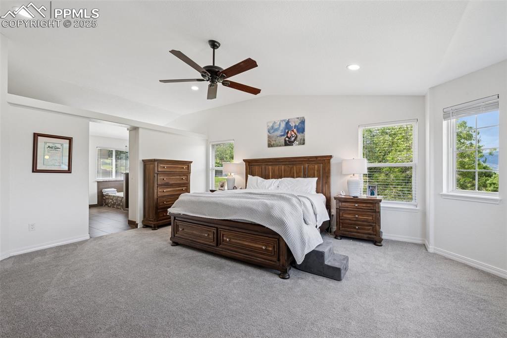 Image 27 of 50: Bedroom featuring multiple windows, light carpet, vaulted ceiling, recessed