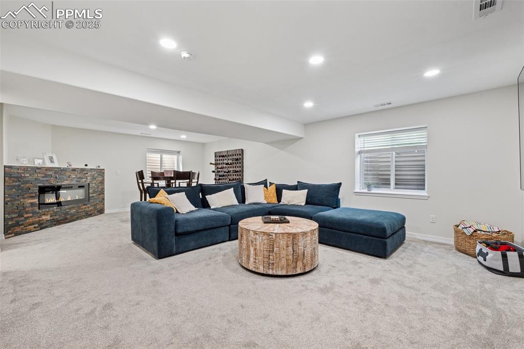 Image 36 of 50: Living area featuring carpet floors, recessed lighting, and a stone firepla