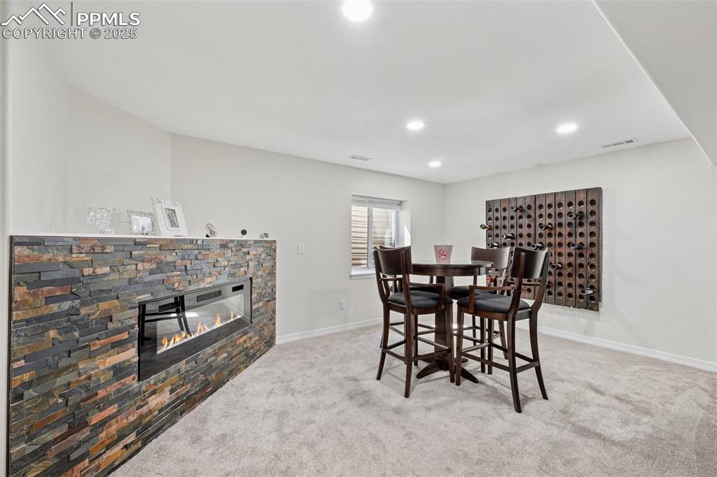 Image 37 of 50: Carpeted dining room with a stone fireplace and recessed lighting