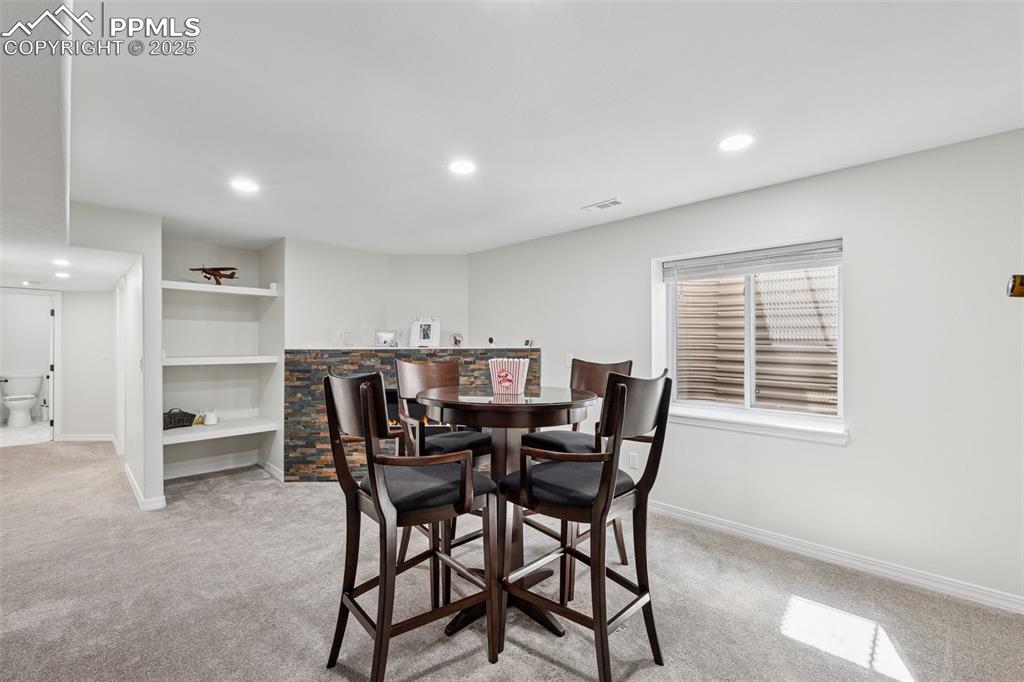 Image 39 of 50: Dining room with light carpet, recessed lighting, bar area, and built in sh